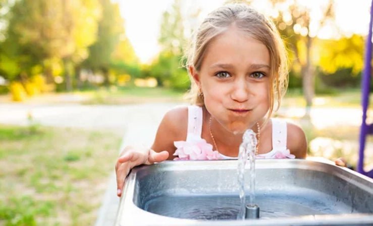 A child enjoys fresh water from a park fountain, underscoring reliable public water quality.