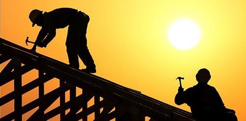 Outdoor construction workers silhouetted against a sunset, highlighting the need for heat stress monitoring.