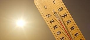 A wooden thermometer in bright sunlight shows a high temperature, emphasizing the importance of temperature monitoring.