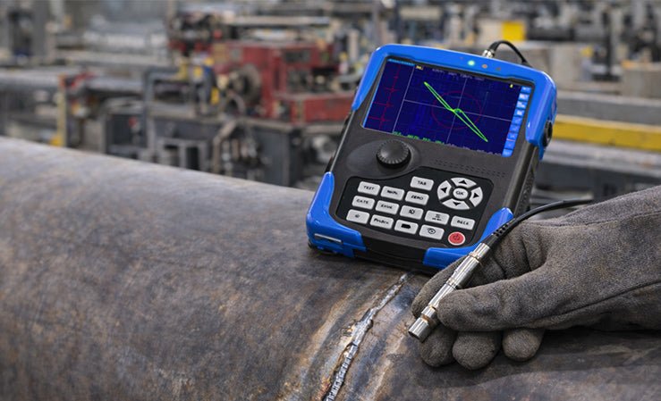 A technician uses a portable NDT device to inspect a pipe weld in an industrial setting.