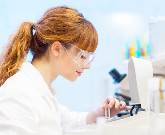 Woman working at a laboratory bench with a centrifuge and other lab equipment.