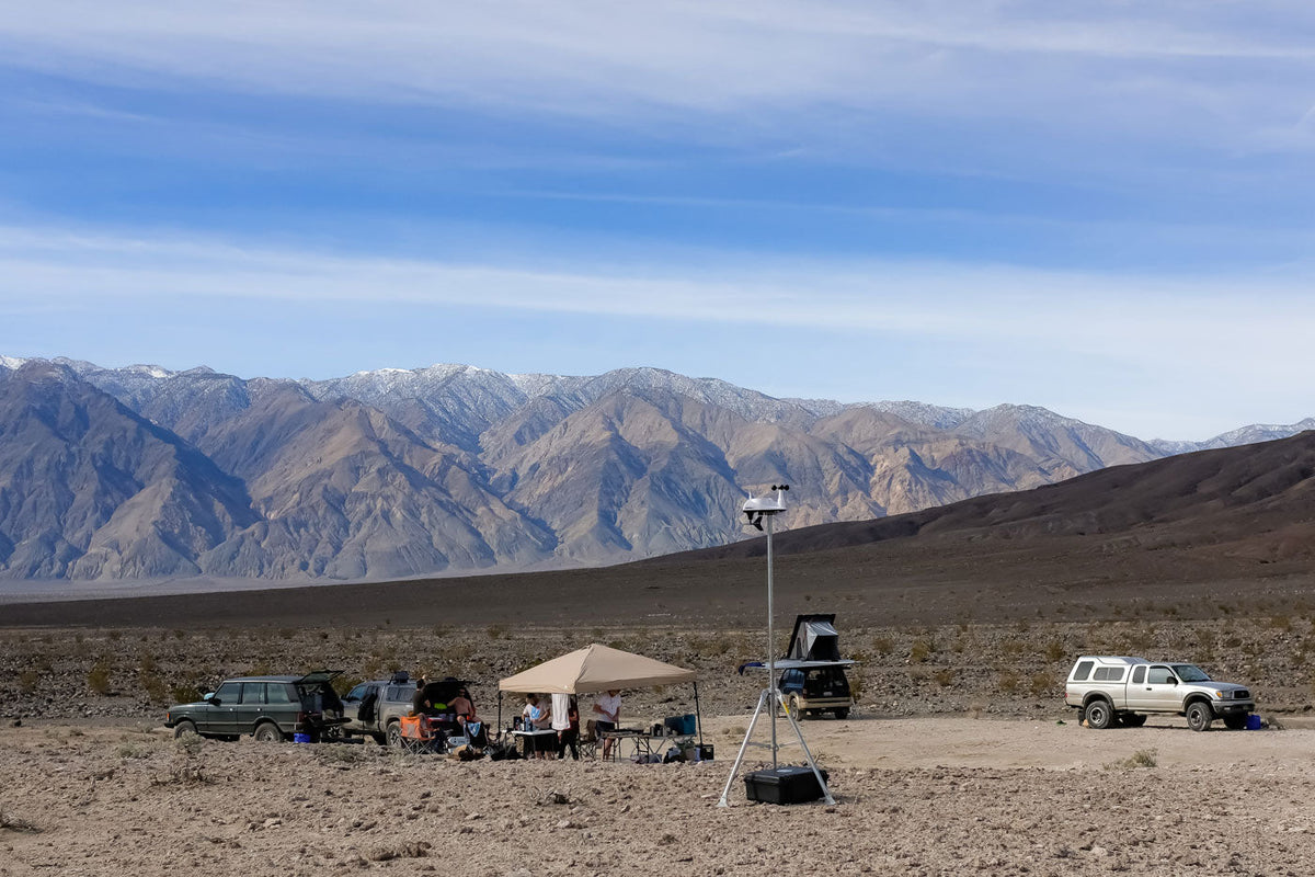 Accessory mounting tripod by Davis Instruments against a desert landscape and blue sky.