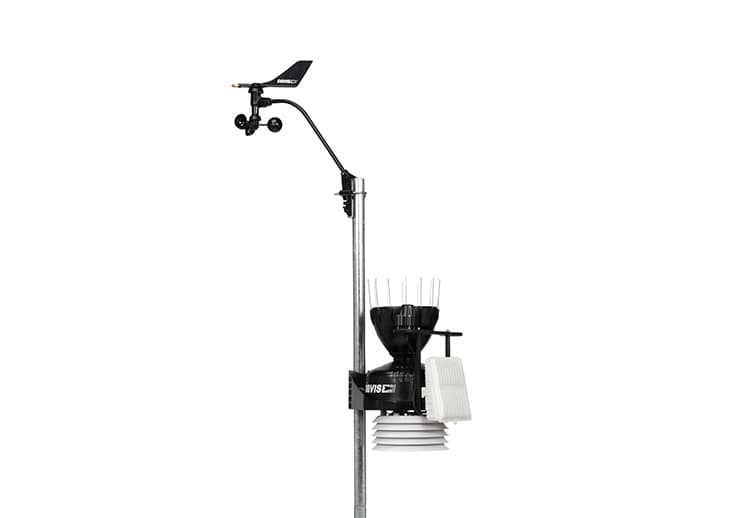Black weather station suite by Davis Instruments with rain collector, anemometer, and temperature sensors attached to a silver pole.
