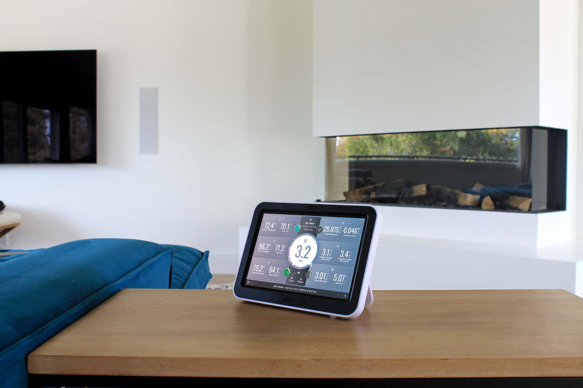 Weather data viewing console by Davis Instruments sitting on a wooden table in a modern living room.
