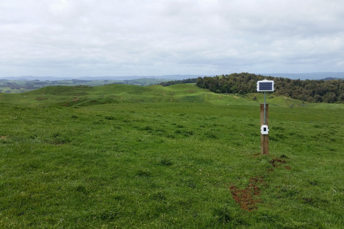 Wireless leaf and soil moisture/temperature station by Davis Instruments on a wood pole in a grassy field landscape.