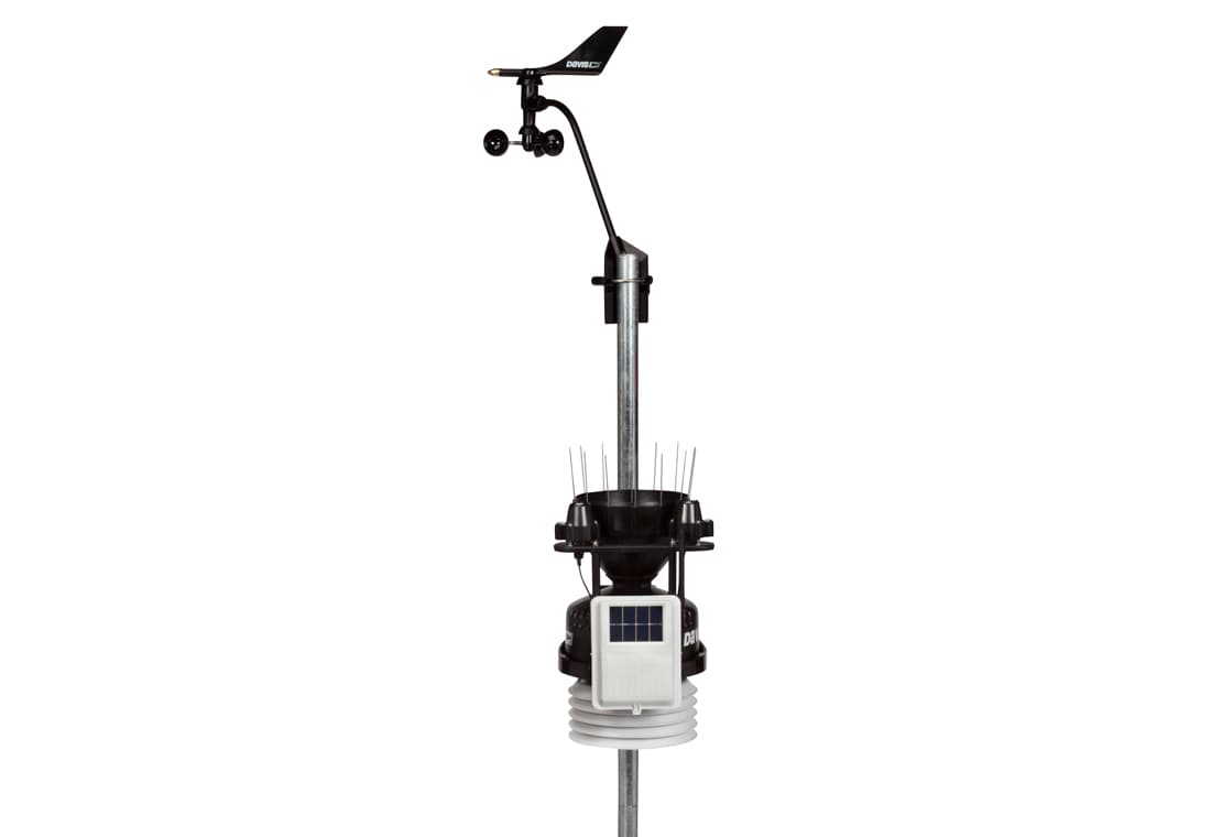 Wireless weather station by Davis Instruments with wind vane and solar panel on a metal pole.
